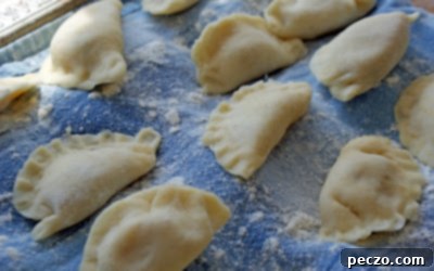 Neatly arranged rows of uncooked homemade perogies on a wooden surface, showcasing their perfect shape and readiness for cooking or freezing.